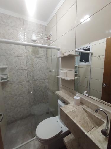 a bathroom with a toilet and a sink and a mirror at Apartamento completo com wi-fi e piscina in Ubatuba