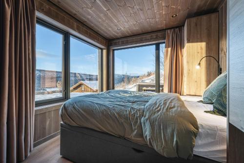 Un dormitorio con una cama en una habitación con ventanas. en New luxury cabin in Geilo with hot tub, mountain views & ski access, en Lii