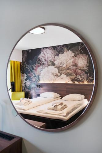 a mirror reflecting a bed in a room at Thon Hotel Saga in Haugesund
