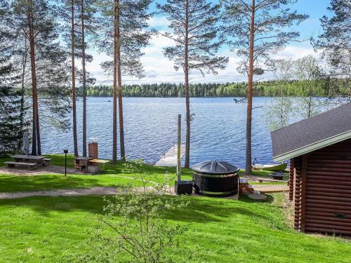 a barbecue on a lawn next to a lake at Holiday Home Nurmirinne by Interhome in Nurmes