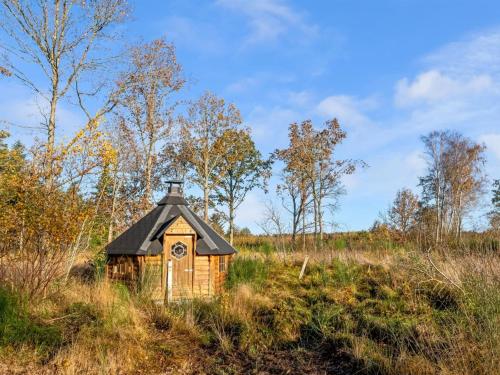a small house with a black roof in a field at Holiday Home Emelia - 4-2km from the sea by Interhome in Byrum