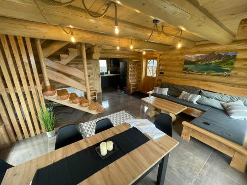 Bali domy RESTORT & SPA في Laskowa: غرفة معيشة كبيرة مع جدران وطاولات خشبية