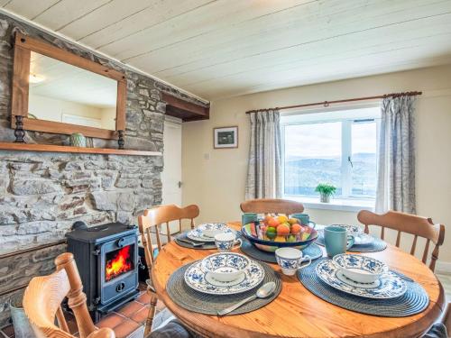 Holiday Home Bunloit Farmhouse by Interhome في Inverfarigaig: غرفة طعام مع طاولة وموقد خشبي