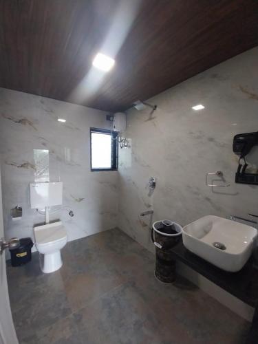 a bathroom with a sink and a toilet and a sink at The KaMP in Murbād