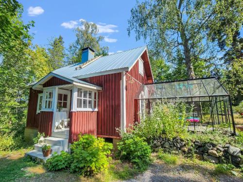 Holiday Home Den lilla röda stugan by Interhome في Kårkulla: كوخ أحمر اللون مزود بدفيئة في حديقة