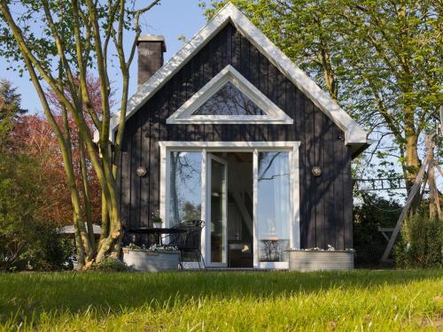 een klein huisje met een schuin dak en een glazen deur bij Ferienhaus Clara in Klein Scharrel