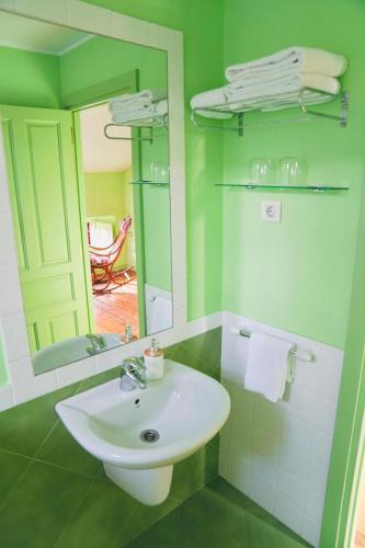 a green bathroom with a sink and a mirror at Casa Los Lomas in Arenas de Iguña