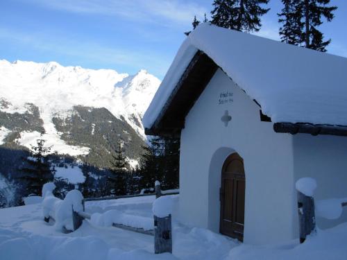 a building covered in snow with mountains in the background at Apart Garten Lutz in Prutz