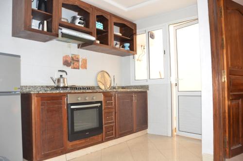 eine Küche mit Holzschränken und einem Herd in der Unterkunft blue wave residense tamraght in Tamraght Ou Fella