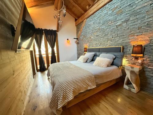 Un dormitorio con una pared de ladrillo y una cama. en Chalet Grand Area, en Briançon