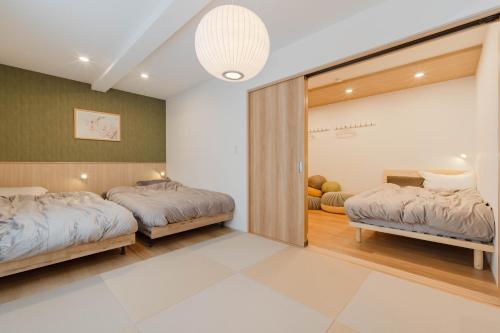 a bedroom with two beds and a sliding glass door at AMBLE Asakusa in Tokyo