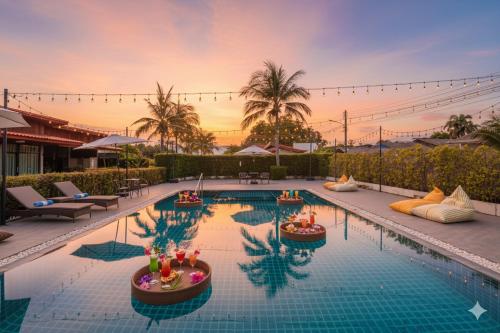 a swimming pool with a sunset in the background at SCN Wellness Spa & Resort Rayong in Ban Chang