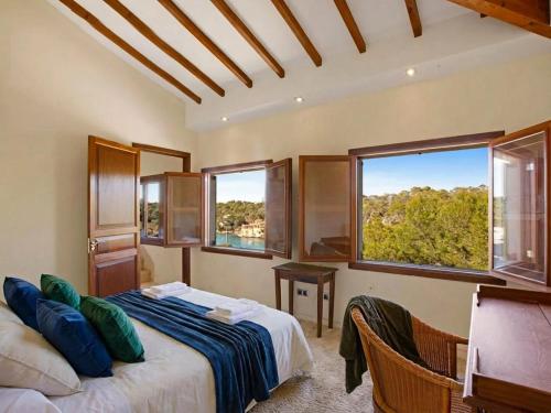 een slaapkamer met een bed en twee ramen bij Villa Cala Figuera in Santanyi