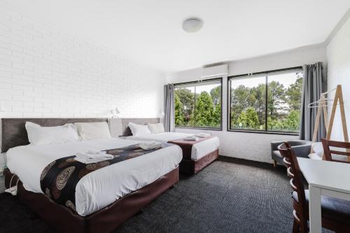 a hotel room with two beds and two windows at The Reserve Hotel in Sale