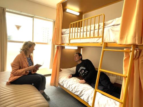 東京にあるサクラホテル日暮里の二段ベッド付きの部屋に座る男女