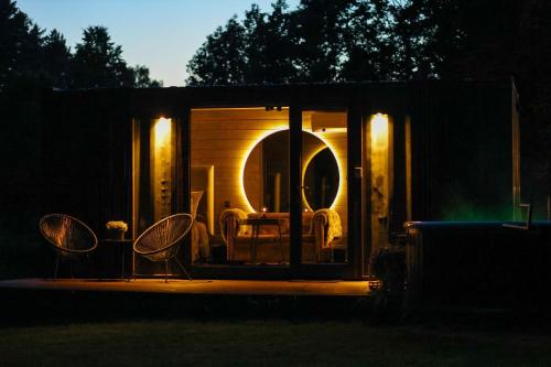a tiny house with a table and chairs in the dark at Reborn Cabins in Pabaži