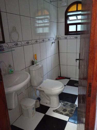 een badkamer met een wit toilet en een wastafel bij Casa Pé na Areia in Mongaguá