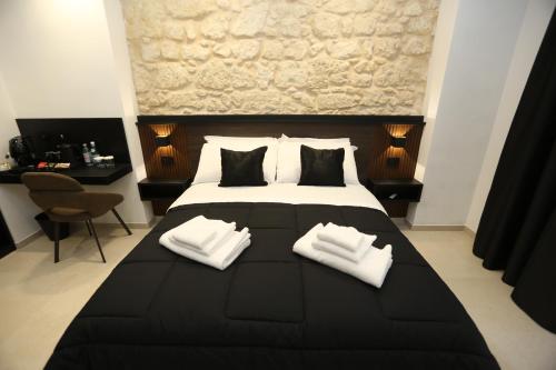 a bedroom with a large black bed with two white towels at Il Moro Luxury Rooms in Siracusa