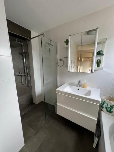 a white bathroom with a sink and a shower at Villa Noordenwind in Julianadorp