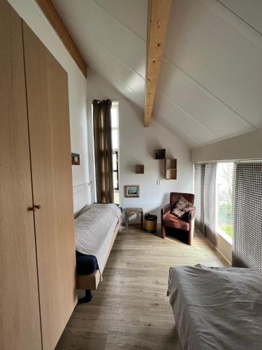 a bedroom with two beds and a chair in it at Villa Noordenwind in Julianadorp
