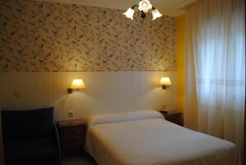 1 dormitorio con 2 camas y pared con papel pintado en Hostal Santa Marta Playa, en Baiona