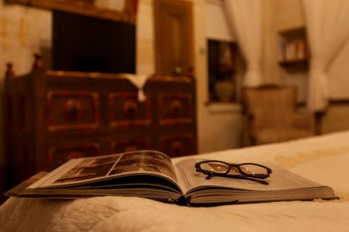 an open book with a pair of glasses sitting on a bed at Kale Konak Cappadocia in Uchisar