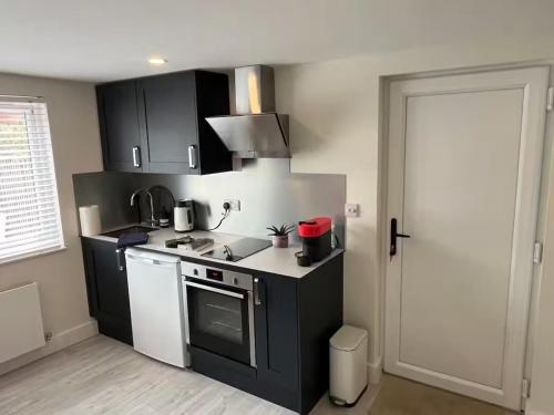 a kitchen with black cabinets and a white stove top oven at River Studio Sleeps 2 with Parking & Dog Friendly in Southampton