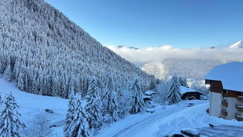 a snow covered mountain with trees and a building at Appartement 8 personnes à Le Biot in Le Biot