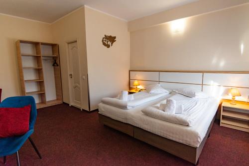 Un dormitorio con una cama grande y una silla azul. en Long Street Hotel, en Brasov