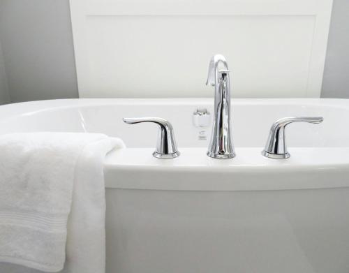 a bathroom sink with two faucets and a bath tub at NL Josephine's Apartment in Kampala