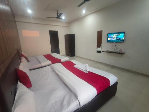 a bedroom with two beds and a flat screen tv at JD Hotel in Doiwāla