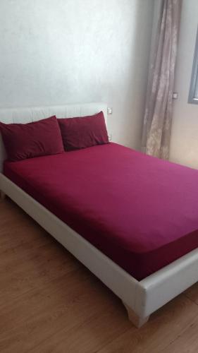 a large bed with a purple blanket on it at Apartment kamal park G39 in Mohammedia