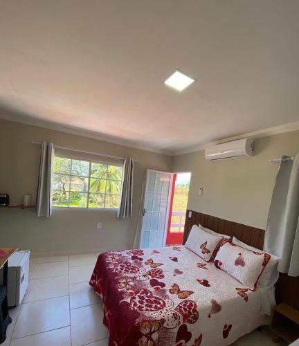 a bedroom with a bed with a red blanket and a window at Suítes Concha do Sol in Maragogi
