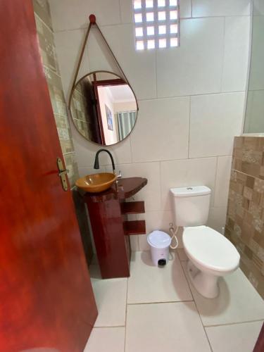 een badkamer met een toilet, een wastafel en een spiegel bij Suítes Concha do Sol in Maragogi