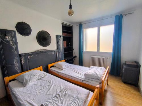 Gîte Le Coquelicot Jardins de Marie في Cerizay: سريرين في غرفة صغيرة بها نافذة