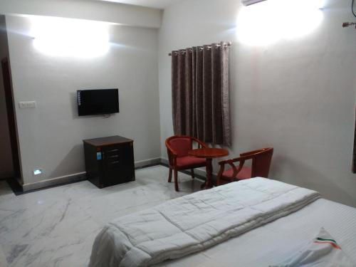 a bedroom with a bed and a table and a tv at Fresh Living Prime Banjara in Hyderabad
