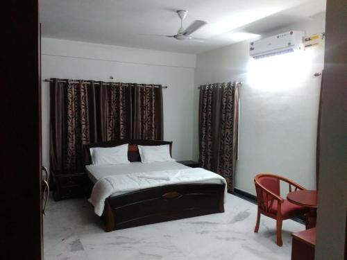 a bedroom with a bed and a chair and curtains at Fresh Living Prime Banjara in Hyderabad