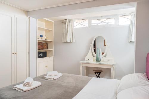 Un dormitorio blanco con una cama y un espejo. en Villa Suites Lagonisi Luxury, en Lagonisi