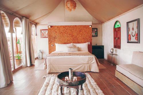 Agafay Yes We Camp Restaurant & Spa في Aït Mazou: غرفة نوم بها سرير كبير وطاولة