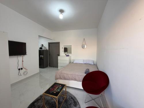 a bedroom with a bed and a red chair at Khalidiya Studio in Abu Dhabi