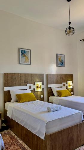 a bedroom with two beds with yellow pillows at Yassers Residence in Er Rachidia