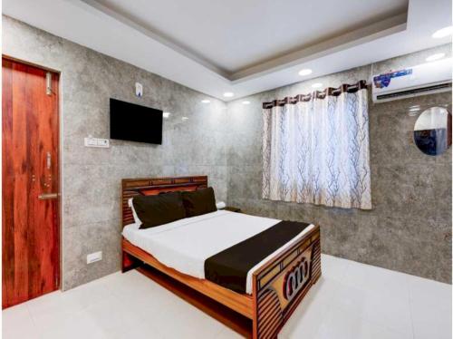 a bedroom with a bed and a flat screen tv at Hotel O Tiruvallur Bus Terminal Formerly SK Vinoth Mahal in Tiruvallūr