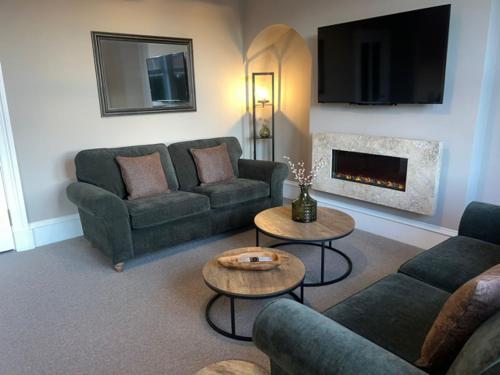 ein Wohnzimmer mit Sofas, Tischen und einem Kamin in der Unterkunft 4 ABBOTSFORD , KELSO Town Centre in Kelso