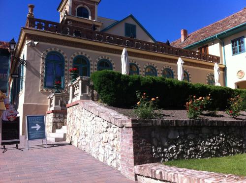 a house with a stone retaining wall and a brick sidewalk at Rosmarinus Apartman in Pécs