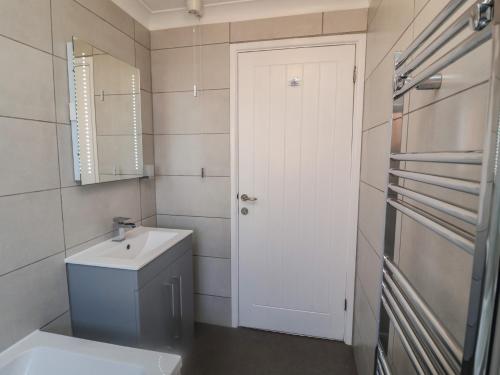 a bathroom with a white door and a sink at Daisy Lodge in Norwich