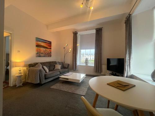 a living room with a couch and a table at Ayr Cozy Corner Apartment in Ayr