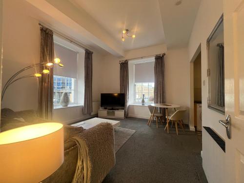 a living room with a couch and a table at Ayr Cozy Corner Apartment in Ayr