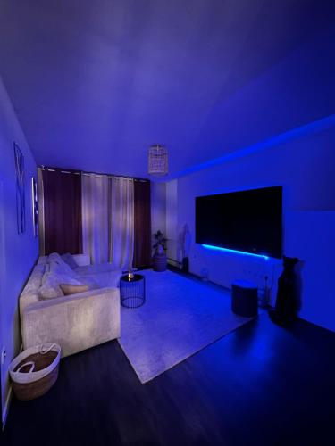 sala de estar con sofá y TV de pantalla grande en Appartement luxueux avec jacuzzi, en Cergy