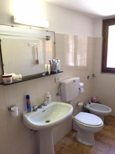 a bathroom with a sink and a toilet and a mirror at Casa Victoria in Tremezzo