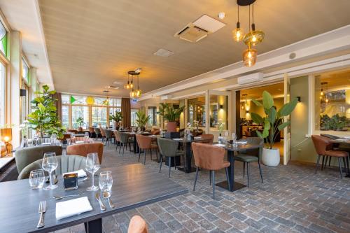 a restaurant with tables and chairs and windows at Fletcher Hotel Apeldoorn in Apeldoorn